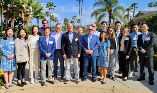 Group of people smiling for photo surrounded by palm trees